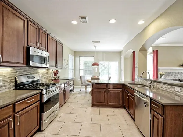 a large kitchen with stainless steel appliances granite countertop a sink and stove top oven