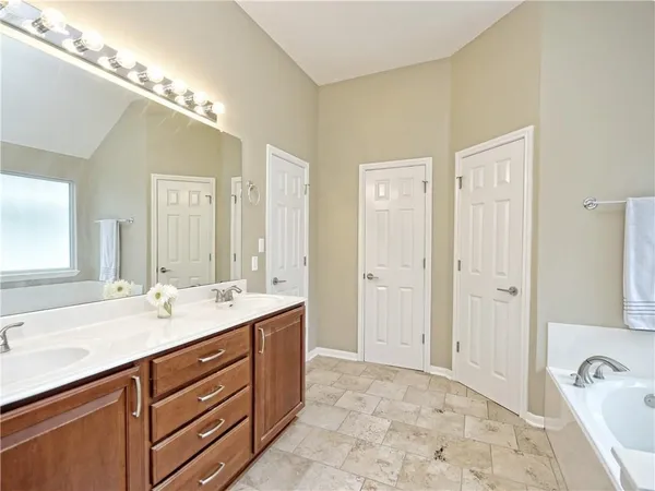 a spacious bathroom with a granite countertop sink a mirror and a shower