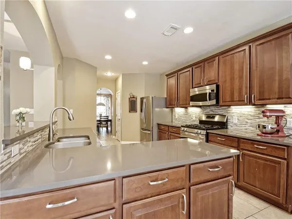 a kitchen with kitchen island granite countertop a sink stainless steel appliances and cabinets