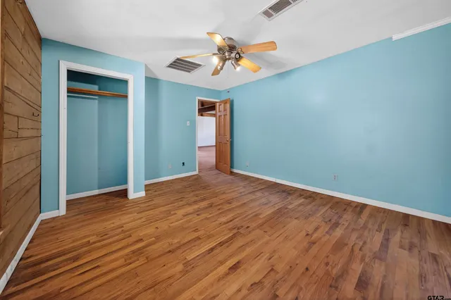a view of a room with wooden floor and a ceiling fan