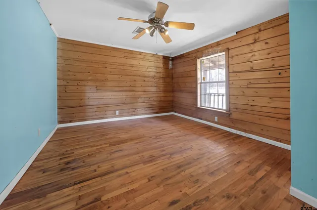a view of empty room with wooden floor and fan