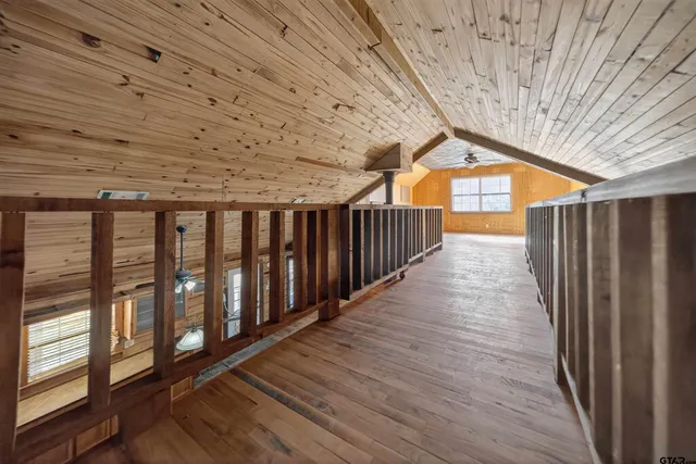 an empty room with wooden floor chandelier fan and windows