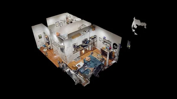 a living room with stainless steel appliances furniture a rug and a kitchen view