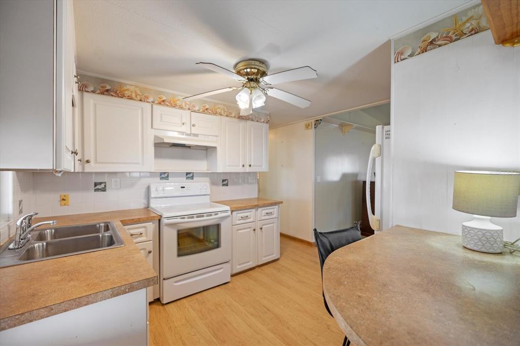 5791 Orange Blossom Road Venice, FL 34293 - Photo 3 of 55 a kitchen with stainless steel appliances a stove a sink dishwasher a refrigerator and white cabinets with wooden floor
