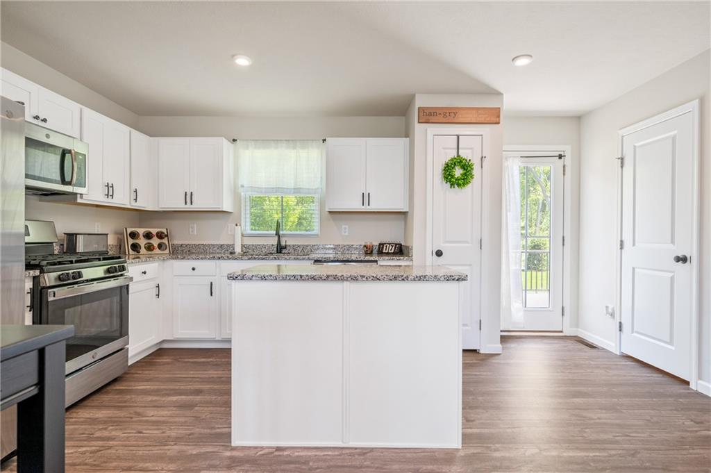 230 James Patrick Place Zelienople, PA 16063 - Photo 6 of 34 a kitchen with kitchen island granite countertop a stove a sink and white cabinets with wooden floor