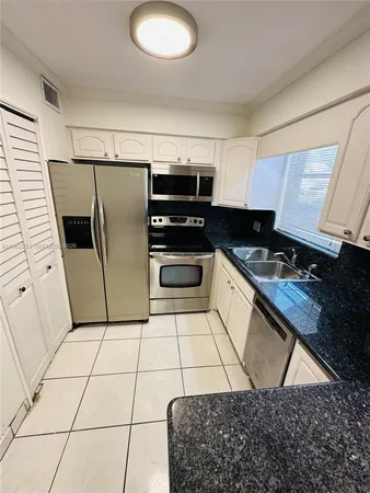 a kitchen with a sink a refrigerator and cabinets
