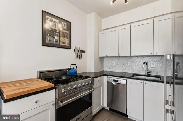 a kitchen with stainless steel appliances granite countertop white cabinets and a stove top oven
