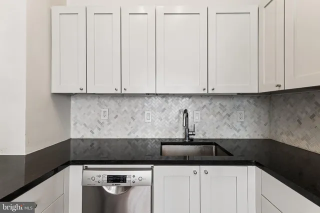 a kitchen with granite countertop white cabinets and sink