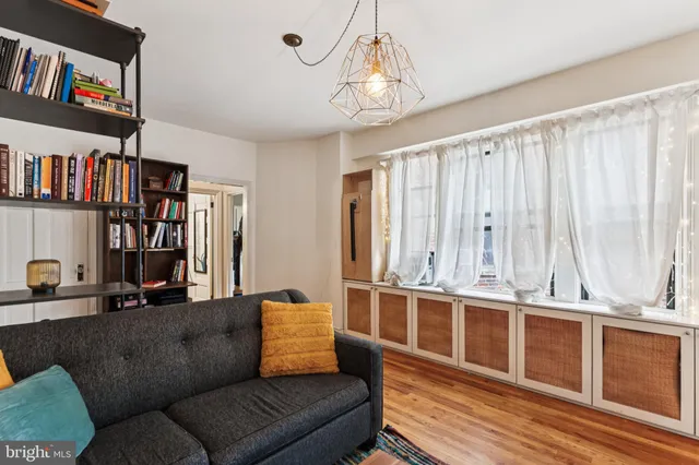 a living room with furniture a bookshelf and a window
