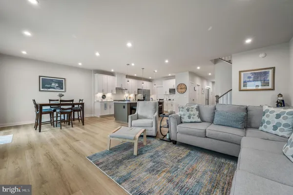a living room with dining table and kitchen view with wooden floor