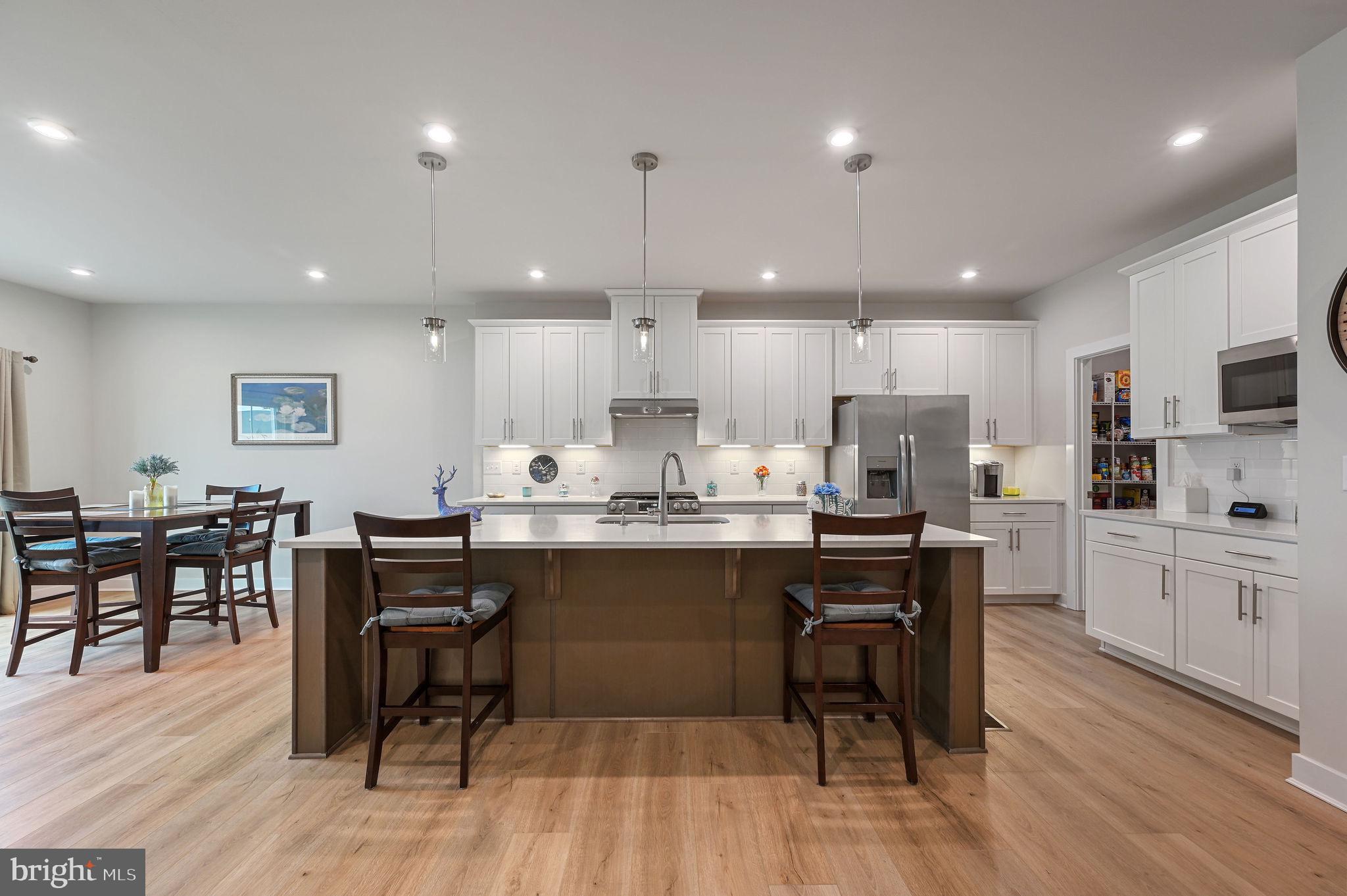 30366 Indigo Way Georgetown, DE 19947 - Photo 10 of 37 a kitchen with stainless steel appliances kitchen island granite countertop a table chairs sink and cabinets