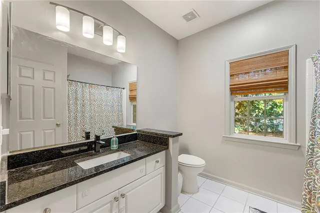 a bathroom with a granite countertop sink a toilet and a window