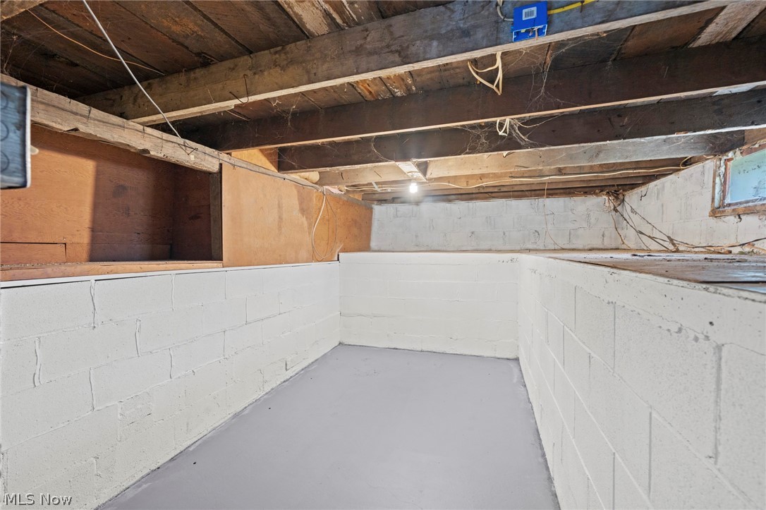 1218 Briggle Road Akron, OH 44320 - Photo 27 of 40 Crawl space with painted concrete block walls and a gray painted concrete floor, featuring exposed wood joists and subflooring