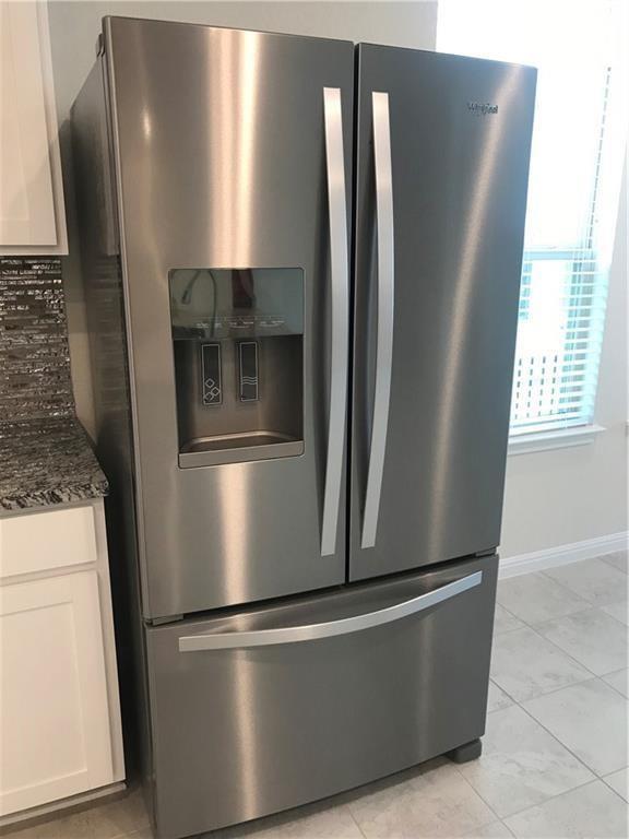 115 Iron Rail Road Dripping Springs, TX 78620 - Photo 3 of 16 Kitchen view of stainless steel fridge with ice dispenser, dark stone counters, and white cabinets