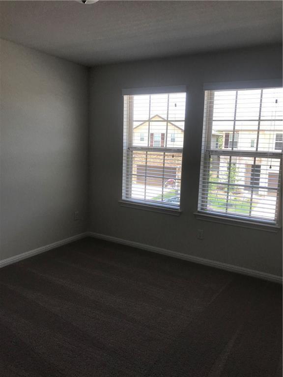 115 Iron Rail Road Dripping Springs, TX 78620 - Photo 10 of 16 Empty room with dark colored carpet and a textured ceiling