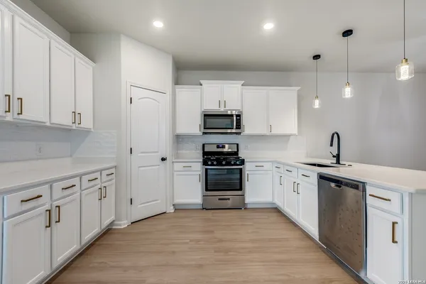 a kitchen with granite countertop a refrigerator stove top oven and cabinets