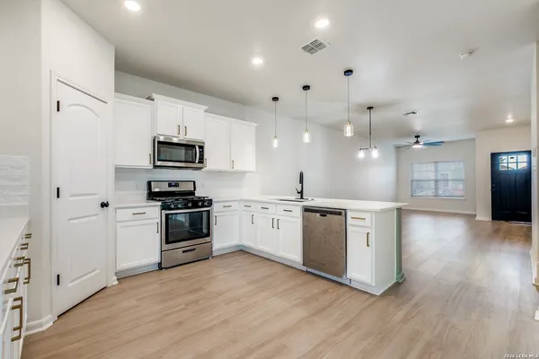 a large kitchen with cabinets wooden floor and stainless steel appliances