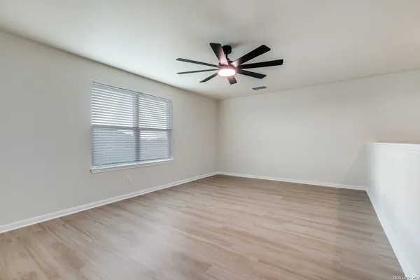 a view of an empty room with a window and wooden floor