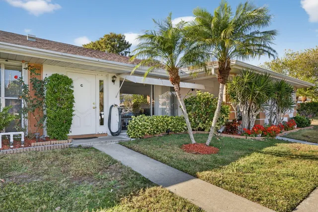 a view of a house with a yard and potted plants