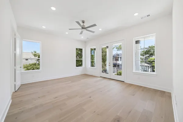 a view of an empty room with a window and wooden floor