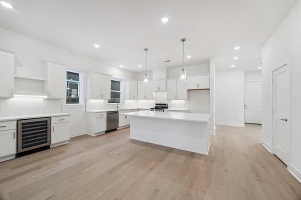 a large white kitchen with white cabinets and stainless steel appliances