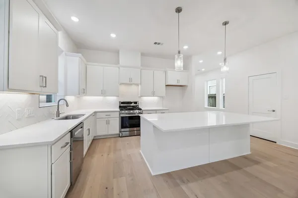 a large kitchen with kitchen island a stove a sink a center island and a wooden floor