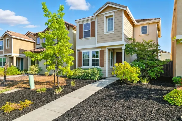 a front view of a house with a yard and potted plants