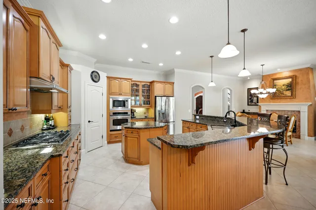 a kitchen with stainless steel appliances granite countertop a refrigerator a stove and a sink with wooden cabinets