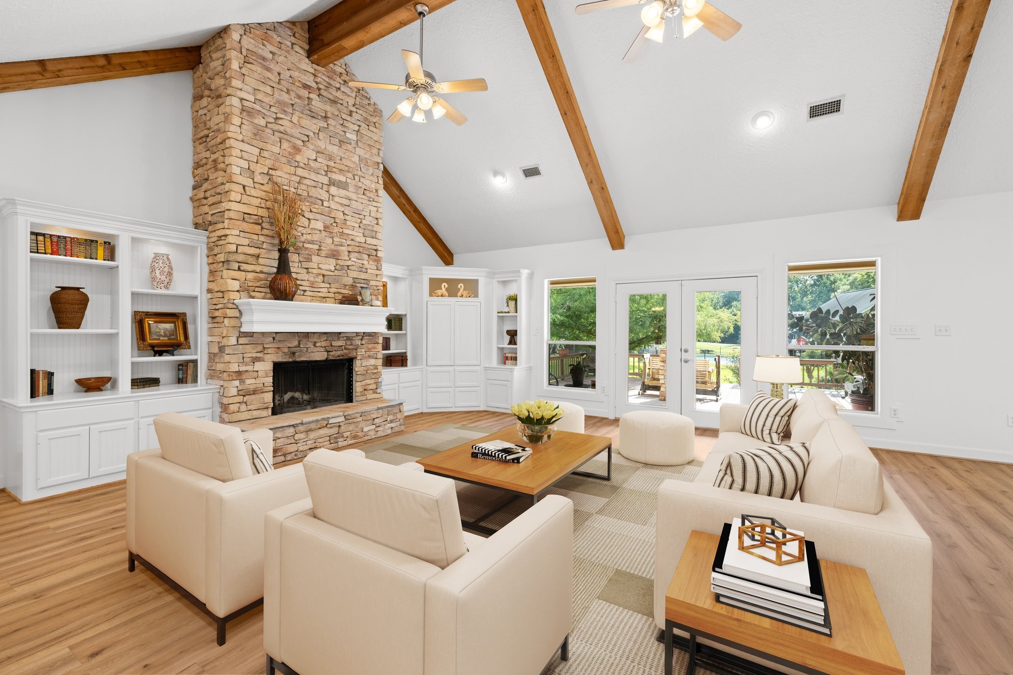 34310 High Point Drive Magnolia, TX 77355 - Photo 8 of 48 This spacious living room features a high vaulted ceiling with exposed wooden beams, a striking stone fireplace, and built-in shelving. Large windows and French doors offer plenty of natural light and views of the outdoor greenery.