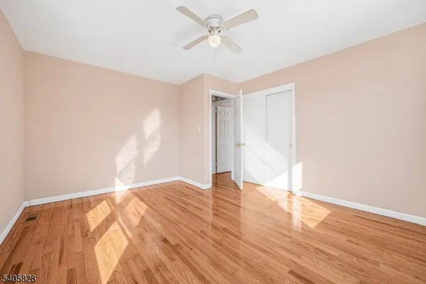an empty room with wooden floor and fan