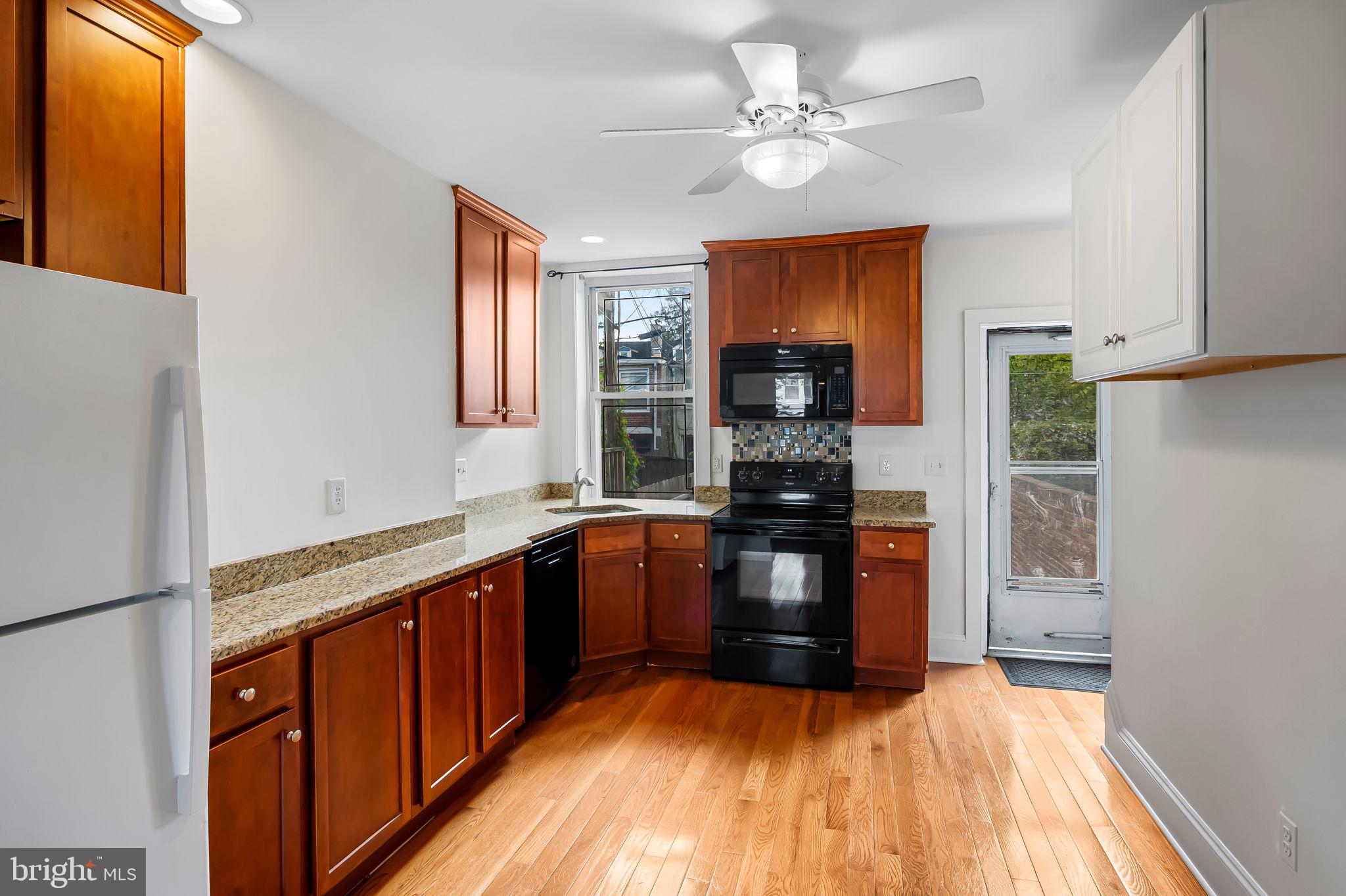 649 Portland Street Baltimore, MD 21230 - Photo 8 of 34 a kitchen with stainless steel appliances granite countertop a refrigerator a sink dishwasher a stove with wooden cabinets and floor