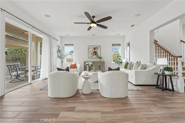 a living room with couches a fireplace and a dining table with wooden floor