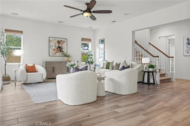 a living room with couches and a dining table with wooden floor