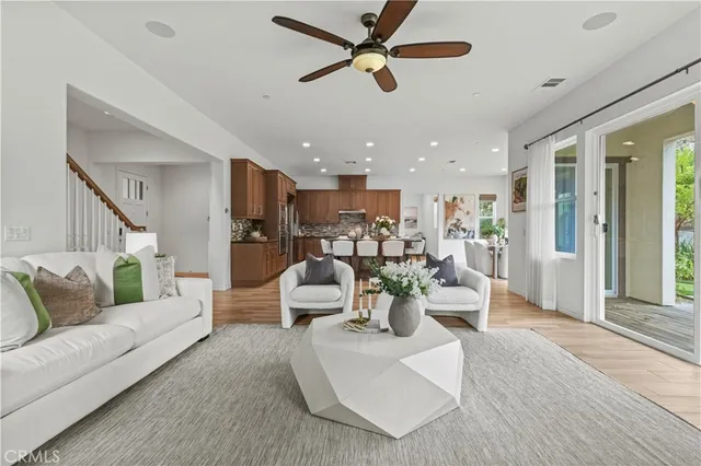 a living room with furniture kitchen view and a wooden floor