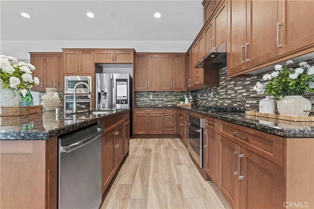 a kitchen with stainless steel appliances granite countertop a stove a sink and a refrigerator