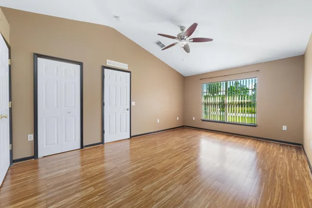 a view of an empty room with wooden floor and a window