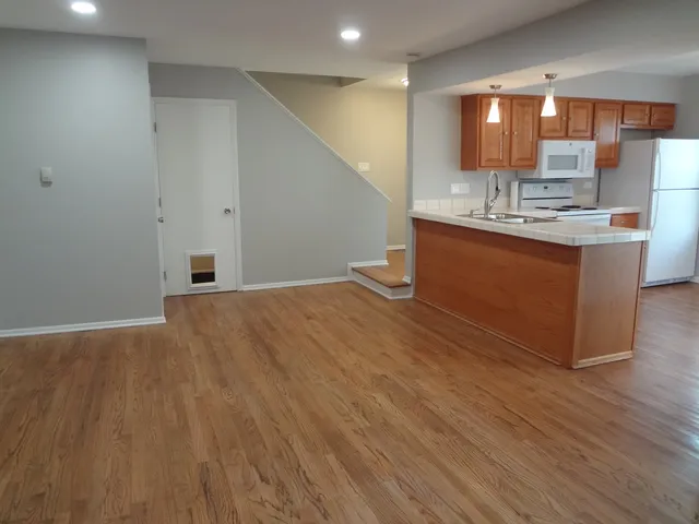 a room with kitchen island granite countertop wooden floors and a sink