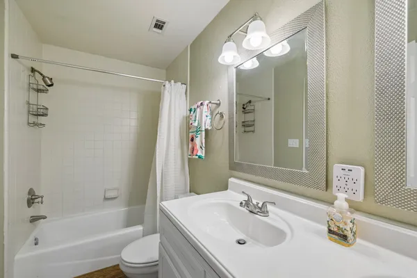 a bathroom with a sink a toilet a mirror and shower