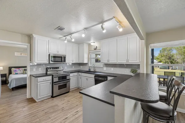 a kitchen with stainless steel appliances granite countertop a stove a sink a microwave a dining table and chairs