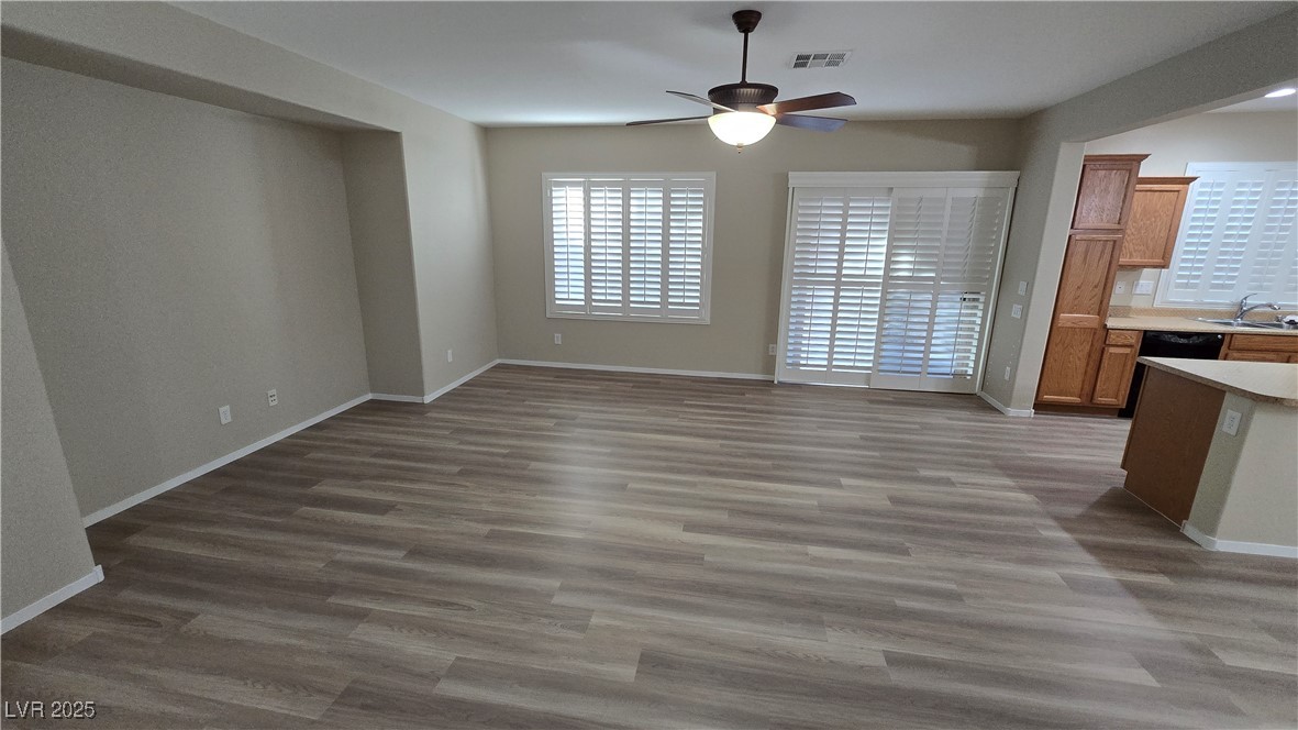 2737 Rimbaud Street Henderson, NV 89044 - Photo 6 of 49 Unfurnished living room with wood finished floors, baseboards, a ceiling fan, and a sink