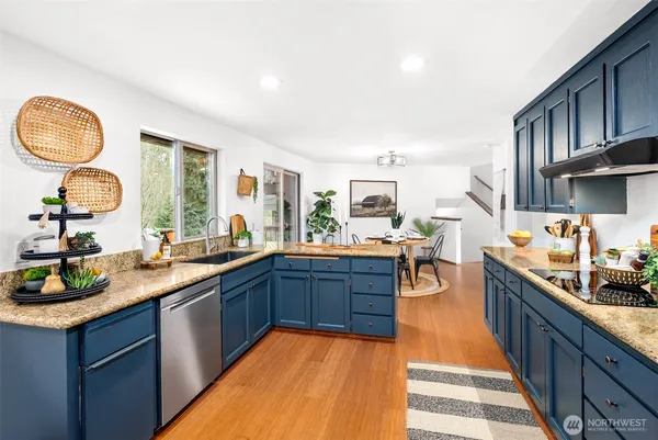 a large kitchen with stainless steel appliances granite countertop a stove a sink dishwasher and cabinets with wooden floor