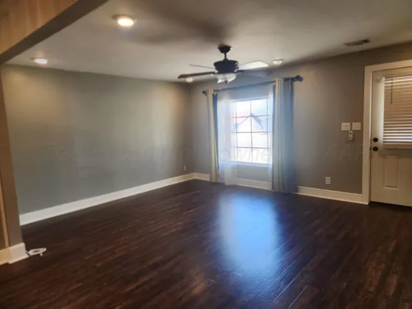 a view of an empty room with wooden floor and a window
