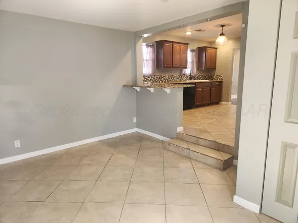 a view of kitchen and empty room with wooden floor