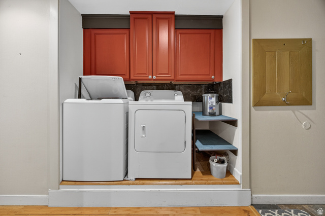 730 East 200 North Logan, UT 84321 - Photo 20 of 28 Dedicated laundry area featuring red upper cabinetry, dark stone-finish backsplash, and wood-finish flooring