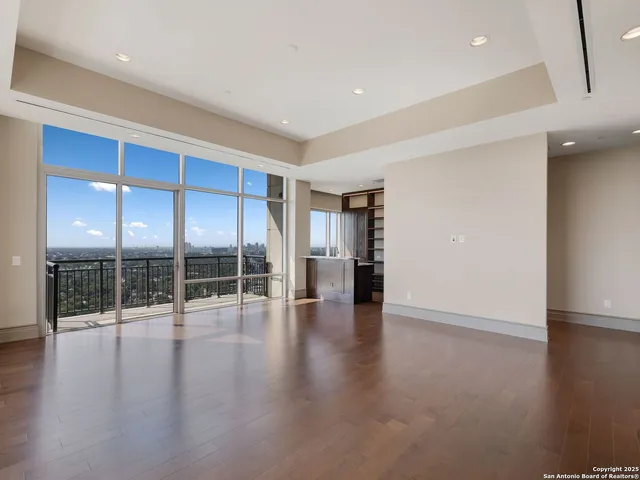 a view of empty room with wooden floor and floor to ceiling window