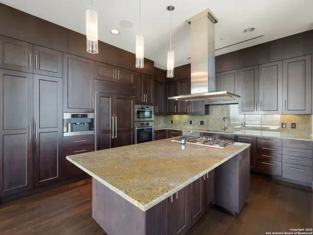a kitchen with stainless steel appliances granite countertop a table chairs sink and cabinets