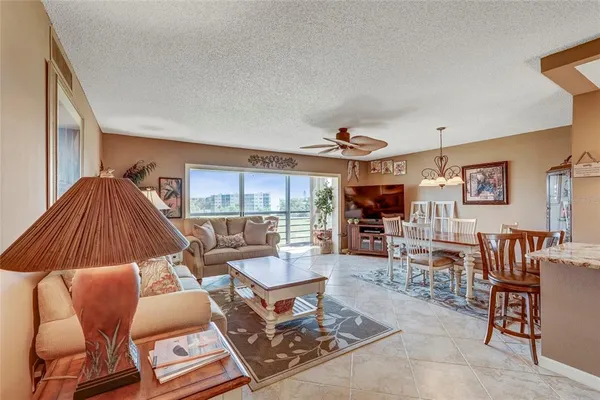 a living room with couches a flat tv screen and a dining table with wooden floor