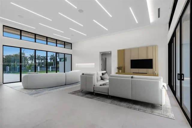 a view of an empty room with kitchen view and a large window