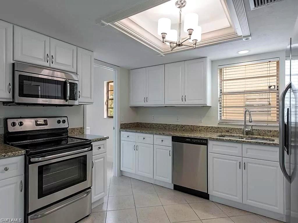 2096 Alamanda Drive, Unit 102 Naples, FL 34102 - Photo 2 of 23 a kitchen with cabinets stainless steel appliances and a window