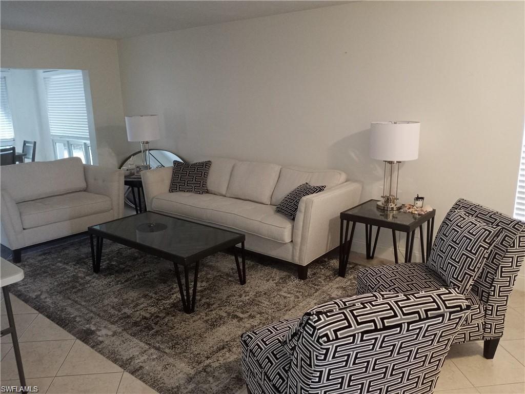 2096 Alamanda Drive, Unit 102 Naples, FL 34102 - Photo 10 of 23 a living room with furniture a lamp a rug and a table